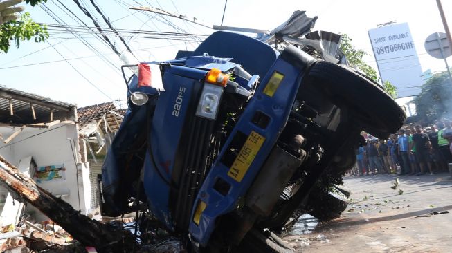 Warga menyaksikan proses evakuasi truk tangki pengangkut BBM berkapasitas 16 ribu liter yang mengalami kecelakaan di Simpang Tiga Sukowidi, Banyuwangi, Jawa Timur, Minggu (25/09/2022).  ANTARA FOTO/Budi Candra Setya