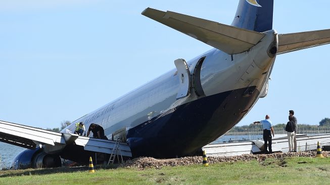 Teknisi dan insinyur bekerja untuk memindahkan Pesawat Kargo Boeing 737 West Atlantic yang tergelincir melewati landasan pacu selama fase pendaratannya di bandara Montpellier, Prancis, Minggu (25/9/2022). [SYLVAIN THOMAS / AFP]
