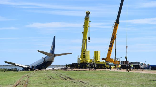 Alat berat digunakan untuk memindahkan Pesawat Kargo Boeing 737 West Atlantic yang tergelincir melewati landasan pacu selama fase pendaratannya di bandara Montpellier, Prancis, Minggu (25/9/2022). [SYLVAIN THOMAS / AFP]
