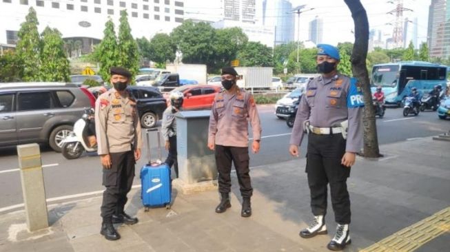 Petugas amankan koper biru misterius yang bikin geger tergeletak di trotoar Polda Metro Jaya, Jakarta, Selasa (27/9/2022). [Dok. Polda Metro Jaya]