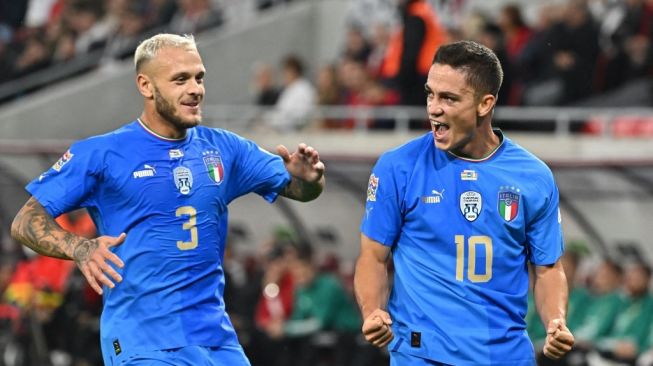 Penyerang Timnas Italia, Giacomo Raspadori (kanan) melakukan selebrasi dengan gelandang Federico Dimarco setelah mencetak gol pertama timnya selama matchday keenam Grup A3 UEFA Nations League 2022-2023 antara Hungaria vs Italia di Budapest pada 26 September 2022. Attila KISBENEDEK / AFP.