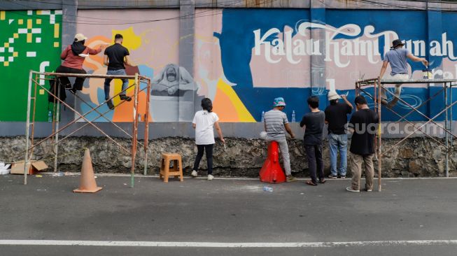 Para seniman menyelesaikan pembuatan mural tematik  di salah satu tembok di Taman Margasatwa Ragunan, Jakarta Selatan. Rabu (28/9/2022). [Suara.com/Alfian Winanto]