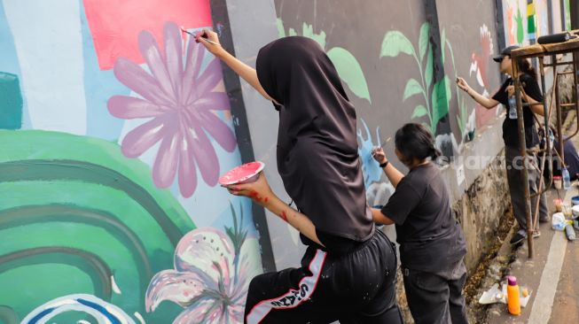 Para seniman menyelesaikan pembuatan mural tematik  di salah satu tembok di Taman Margasatwa Ragunan, Jakarta Selatan. Rabu (28/9/2022). [Suara.com/Alfian Winanto]