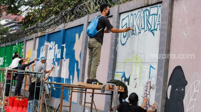 Para seniman menyelesaikan pembuatan mural tematik  di salah satu tembok di Taman Margasatwa Ragunan, Jakarta Selatan. Rabu (28/9/2022). [Suara.com/Alfian Winanto]