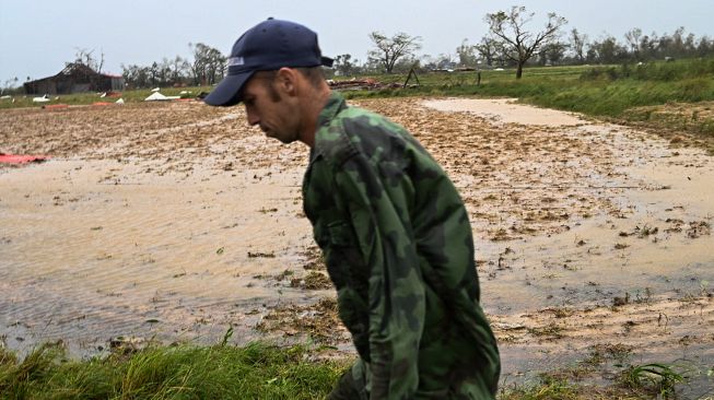 Seorang pria berjalan di dekat ladang tembakau yang terendam banjir usai diterjang Badai Ian di Puerta de Golpe, Kuba, Selasa (27/9/2022). [ADALBERTO ROQUE / AFP]