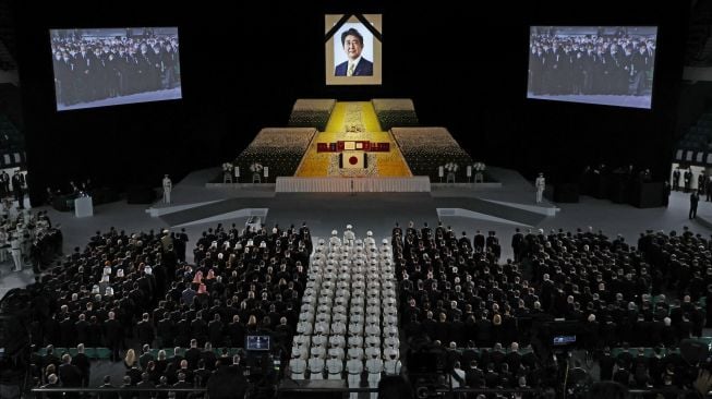 Potret mantan perdana menteri Jepang Shinzo Abe tergantung di atas panggung saat pemakaman kenegaraannya di Nippon Budokan, Tokyo, Jepang, Selasa (27/9/2022). [Takashi Aoyama / POOL / AFP]