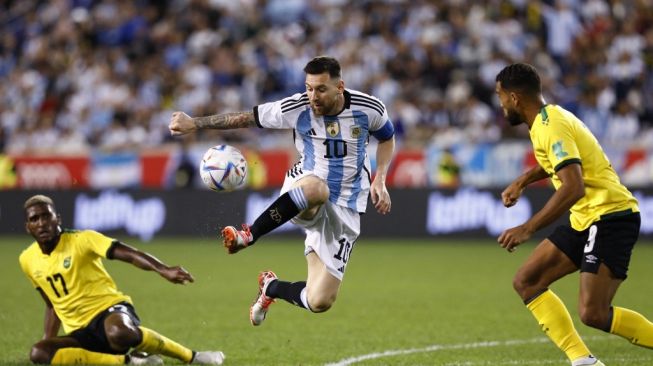 Penyerang Timnas Argentina Lionel Messi (kiri) berebut bola dengan pemain Jamaika selama pertandingan persahabatan internasional FIFA Matchday antara Argentina vs Jamaika di Red Bull Arena di Harrison, New Jersey, pada 27 September 2022.
Andres Kudacki / AFP.