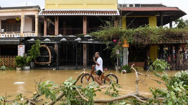 Seorang pria berjalan di jalan yang banjir setelah Topan Noru di kota Hoi An, provinsi Quang Nam pada Rabu (28/9/2022). [Foto: Nhac NGUYEN / AFP]