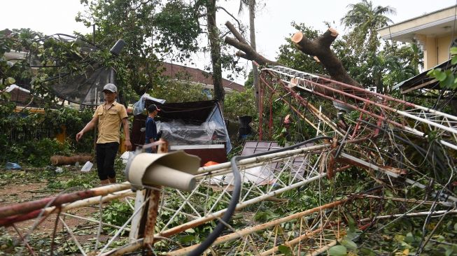 Seorang pria berjalan melewati bangunan yang runtuh gegara topan Noru di kota Hoi An, provinsi Quang Nam pada Rabu (28/9/2022). [Foto: Nhac NGUYEN / AFP]