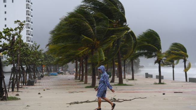 Seorang pria berjalan di sepanjang pantai setelah melewati topan Noru di kota Hoi An, provinsi Quang Nam pada Rabu (28/9/2022). [Foto: Nhac NGUYEN / AFP]