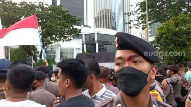 Penampakan polisi terluka di keningnya usai adu dorong dengan massa BEM SI Kerakyatan saat demonstrasi di kawasan Patung Kuda, Jakarta. (Suara.com/Rakha)