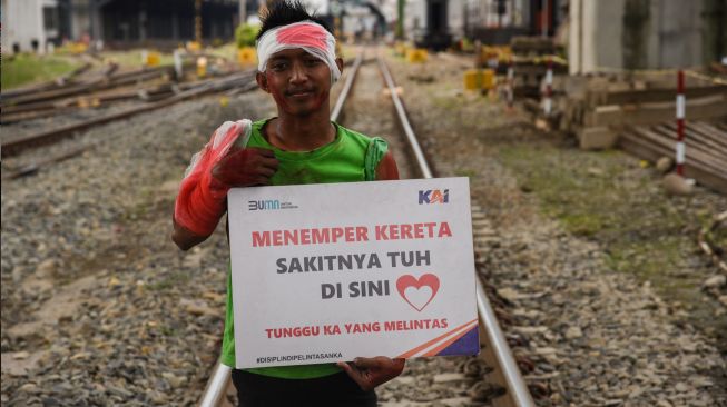 Seorang relawan dari komunitas Railfans melakukan sosialisasi keselamatan di perlintasan sebidang di kawasan Jalan Prof Ahmad Yamin, Kota Medan, Sumatera Utara, Jumat (30/9/2022). [ANTARA FOTO/Fransisco Carolio/Ief/foc]
