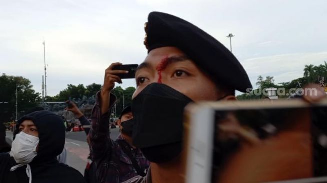 Penampakan polisi terluka di keningnya usai adu dorong dengan massa BEM SI Kerakyatan saat demonstrasi di kawasan Patung Kuda, Jakarta. (Suara.com/Rakha)