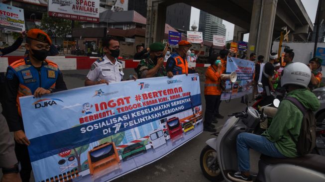 Sejumlah petugas dari PT KAI melakukan sosialisasi keselamatan di perlintasan sebidang kereta api kawasan Jalan Prof Ahmad Yamin, Kota Medan, Sumatera Utara, Jumat (30/9/2022). [ANTARA FOTO/Fransisco Carolio/Ief/foc]
