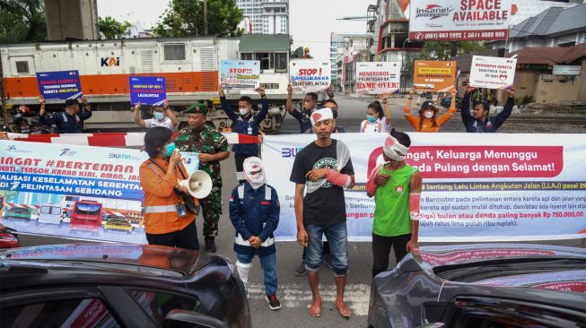 Sejumlah petugas dari PT KAI melakukan sosialisasi keselamatan di perlintasan sebidang kereta api kawasan Jalan Prof Ahmad Yamin, Kota Medan, Sumatera Utara, Jumat (30/9/2022). [ANTARA FOTO/Fransisco Carolio/Ief/foc]
