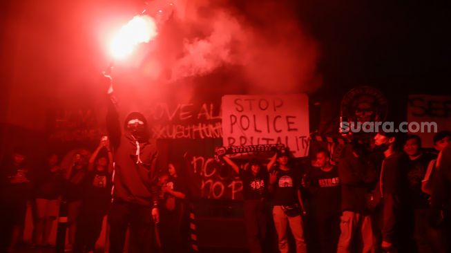 Ultras Garuda bersama Gabungan suporter klub di Indonesia menyalakan flare saat melakukan aksi 1000 lilin dan tabur bunga di depan Kompleks Gelora Bung Karno, Jakarta Pusat, Minggu (2/10/2022). [Suara.com/Alfian Winanto]