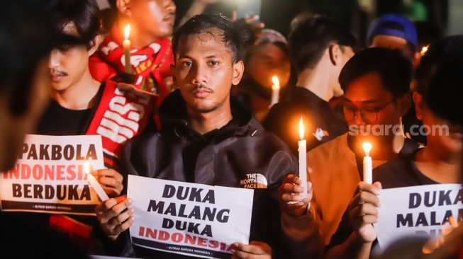 Ultras Garuda bersama Gabungan suporter klub di Indonesia melakukan aksi 1000 lilin dan tabur bunga di depan Kompleks Gelora Bung Karno, Jakarta Pusat, Minggu (2/10/2022). [Suara.com/Alfian Winanto]