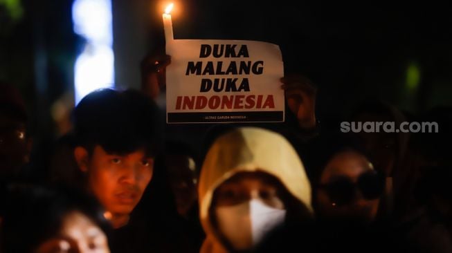 Ultras Garuda bersama Gabungan suporter klub di Indonesia melakukan aksi 1000 lilin dan tabur bunga di depan Kompleks Gelora Bung Karno, Jakarta Pusat, Minggu (2/10/2022). [Suara.com/Alfian Winanto]