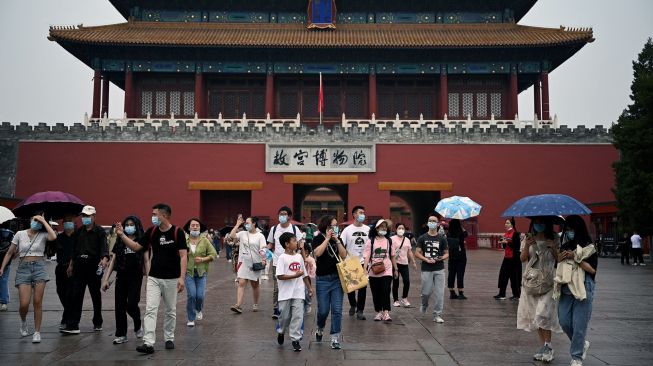 Orang-orang berjalan dari pintu keluar Kota Terlarang saat hari pertama libur Hari Nasional China di Beijing, Sabtu (1/20/2022). [Noel SELIS / AFP]
