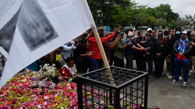 Suporter Arema FC (Aremania) berdoa di Patung Singa Stadion Kanjuruhan, Malang, jawa Timur, Minggu (2/10/2022). [ANTARA FOTO/Zabur Karuru/foc]