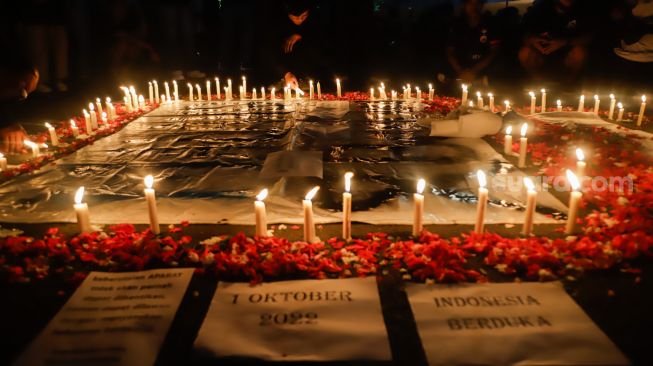 Ultras Garuda bersama Gabungan suporter klub di Indonesia melakukan aksi 1000 lilin dan tabur bunga di depan Kompleks Gelora Bung Karno, Jakarta Pusat, Minggu (2/10/2022). [Suara.com/Alfian Winanto]