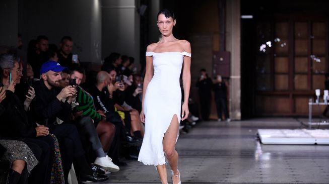 Model Bella Hadid tampil di catwalk dengan slip dress yang disemprot dengan kain Fabrican Spray-on selama peragaan busana Coperni Spring-Summer 2023 yang merupakan bagian dari Paris Fashion Week di Paris, Prancis, Jumat (30/9/2022). [JULIEN DE ROSA / AFP]
