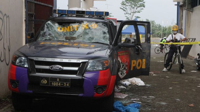 Seorang warga melihat mobil satuan K-9 milik Polres Malang yang hancur akibat kerusuhan di Stadion Kanjuruhan, Malang, Jawa Timur, Minggu (2/10/2022). [ANTARA FOTO/Ari Bowo Sucipto/foc]