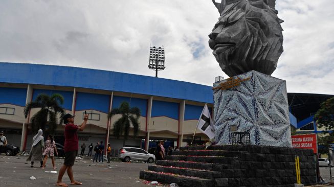 Warta memotret bunga yang ditabur superter Arema FC (Aremania) di Patung Singa Stadion Kanjuruhan, Malang, jawa Timur, Minggu (2/10/2022). [ANTARA FOTO/Zabur Karuru/foc]