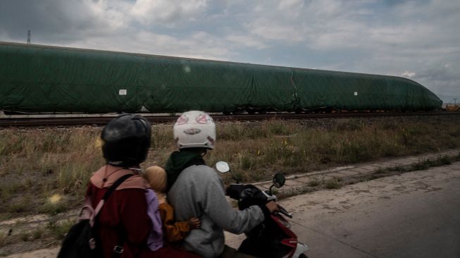 Pengendara sepeda motor melintas di dekat rangkaian gerbong Kereta Cepat Jakarta-Bandung di Tegalluar, Bandung, Jawa Barat, Sabtu (1/10/2022). [ANTARA FOTO/Aprillio Akbar/tom]