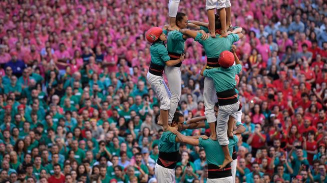 Anggota tim menara manusia "Castellers de Vilafranca" membentuk "castell" (menara manusia) selama kompetisi 'castells' edisi ke-28 di arena Tarraco di Tarragona, Catalunya, Spanyol, Minggu (2/10/2022). [Josep LAGO / AFP]