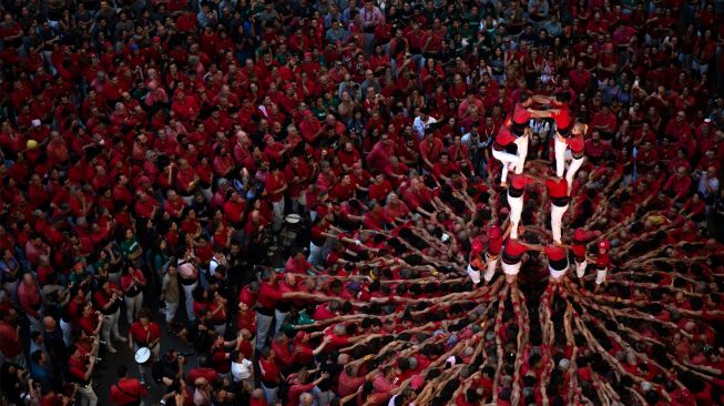 Anggota tim menara manusia "Jove de Valls" membentuk "castell" (menara manusia) selama kompetisi 'castells' edisi ke-28 di arena Tarraco di Tarragona, Catalunya, Spanyol, Minggu (2/10/2022). [Josep LAGO / AFP]