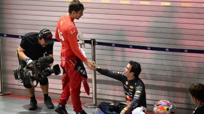 Pebalap Red Bull Racing Sergio Perez (kanan) yang menjuarai F1 GP Singapura menyapa pebalap Ferrari yang berada di posisi kedua, Charles Leclerc (kiri) setelah balapan malam di Marina Bay Street Circuit di Singapura pada 2 Oktober 2022. MOHD RASFAN / AFP