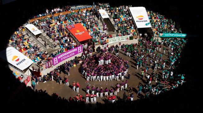 Anggota tim "Moixiganguers Igualada" berusaha membentuk "castell" (menara manusia) selama kompetisi 'castells' edisi ke-28 di arena Tarraco di Tarragona, Catalunya, Spanyol, Minggu (2/10/2022). [Josep LAGO / AFP]