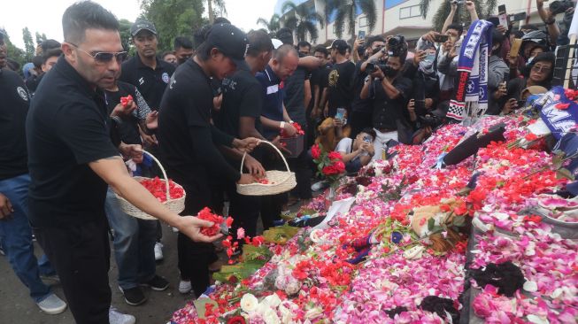 Sejumlah pemain dan official Arema FC menaburkan bunga di depan patung Singa Tegar kawasan Stadion Kanjuruhan, Malang, Jawa Timur, Senin (3/10/2022). [ANTARA FOTO/Prasetia Fauzani/rwa]