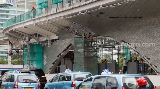 Pekerja menyelesaikan proyek revitalisasi Halte Transjakarta Bundaran HI, Jakarta Pusat, Selasa (4/10/2022). [Suara.com/Alfian Winanto]