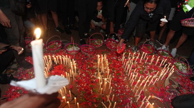 Suporter Persebaya memegang lilin saat mengikuti doa bersama di Tugu Pahlawan, Surabaya, Jawa Timur, Senin (3/10/2022).  ANTARA FOTO/Didik Suhartono