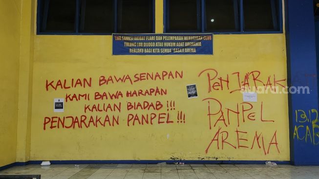 Sejumlah coretan berisi kekecewaan menghiasi dinding Stadion Kanjuruhan Malang, Jawa Timur, Selasa (4/10/2022). Mereka minta agar kasus Tragedi Kanjuruhan yang menelan lebih dari 100 orang meninggal dunia diusut tuntas. [Suara.com/Dimas Angga]