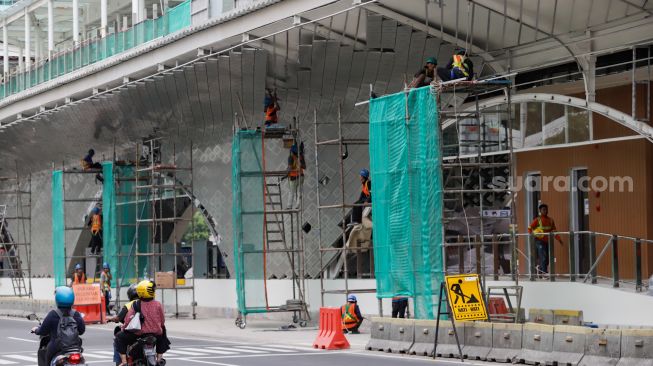 Pekerja menyelesaikan proyek revitalisasi Halte Transjakarta Bundaran HI, Jakarta Pusat, Selasa (4/10/2022). [Suara.com/Alfian Winanto]