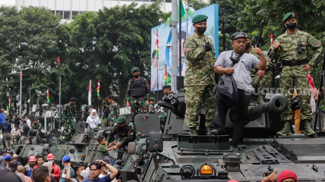 Warga berswafoto dengan kendaraan alutsista milik TNI yang dipamerkan di Bundaran HI, Jakarta Selatan, Rabu (5/10/2022). [Suara.com/Alfian Winanto]