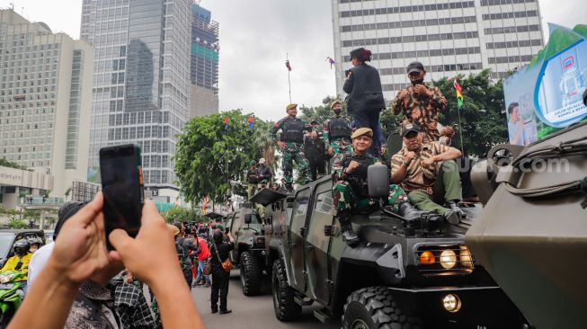 Warga berswafoto dengan kendaraan alutsista milik TNI yang dipamerkan di Bundaran HI, Jakarta Selatan, Rabu (5/10/2022). [Suara.com/Alfian Winanto]