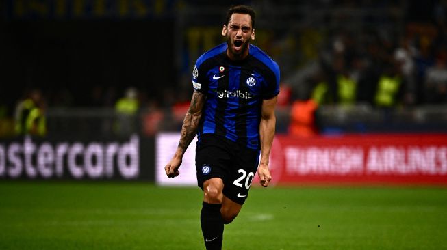 Gelandang Inter Milan Hakan Calhanoglu melakukan selebrasi setelah membuka skor selama pertandingan sepak bola Grup C Liga Champions antara Inter Milan melawan Barcelona di Stadion Giuseppe Meazza, Milan, Rabu (5/10/2022) dini hari WIB.  Marco BERTORELLO / AFP
