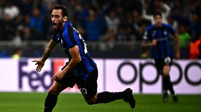 Gelandang Inter Milan Hakan Calhanoglu melakukan selebrasi setelah membuka skor selama pertandingan sepak bola Grup C Liga Champions antara Inter Milan melawan Barcelona di Stadion Giuseppe Meazza, Milan, Rabu (5/10/2022) dini hari WIB.  Marco BERTORELLO / AFP
