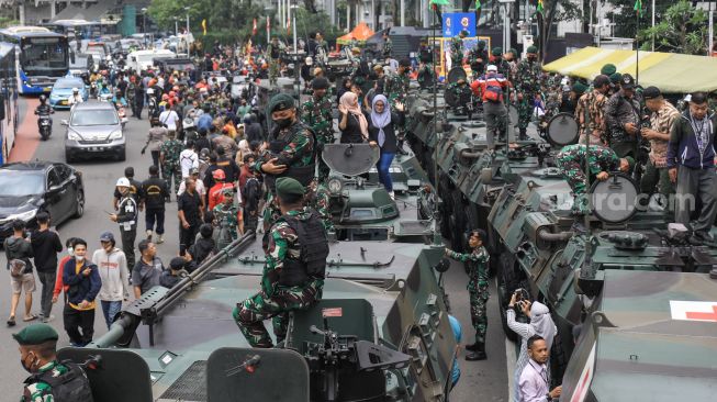 Warga melihat kendaraan alutsista milik TNI yang dipamerkan di Bundaran HI, Jakarta Selatan, Rabu (5/10/2022). [Suara.com/Alfian Winanto]