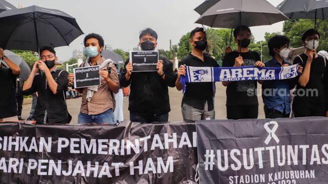 Pegiat Hak Asasi Manusia (HAM) membawa poster dan spanduk Arema saat aksi Kamisan di depan Istana Merdeka, Jakarta Pusat, Kamis (6/10/2022).
[Suara.com/Alfian Winsnto]