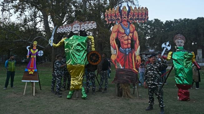 Seorang polisi paramiliter mengambil foto selfie di depan patung raja iblis Rahwana sebelum membakarnya pada Festival Hindu Dussehra di Srinagar, India, Rabu (5/10/2022).  [Tauseef MUSTAFA / AFP]