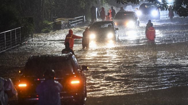 Petugas Penanganan Prasarana dan Sarana Umum (PPSU) mengimbau pengendara mobil saat menerjang banjir di kawasan Jeruk Purut, Jakarta Selatan, Kamis (6/10/2022). [ANTARA FOTO/M Risyal Hidayat/YU]