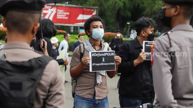 Pegiat Hak Asasi Manusia (HAM) membawa poster dan spanduk Arema saat aksi Kamisan di depan Istana Merdeka, Jakarta Pusat, Kamis (6/10/2022).
[Suara.com/Alfian Winsnto]