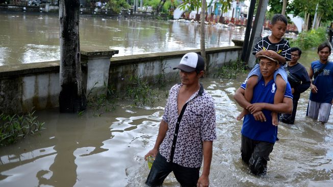 Warga berjalan menerobos banjir yang menggenangi kawasan Legian, Badung, Bali, Sabtu (8/10/2022). ANTARA FOTO/Fikri Yusuf
