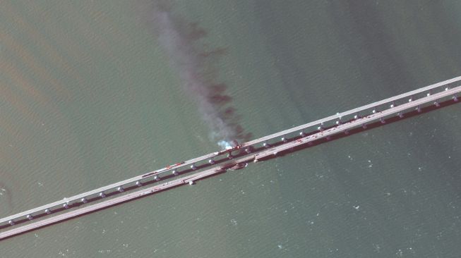 Asap hitam mengepul dari kebakaran akibat sebuah truk yang meledak di jembatan Kerch yang menghubungkan Krimea dan Rusia di semenanjung Kerch, Sabtu (8/10/2022). [Handout / Satellite image ©2019 Maxar Technologies / AFP] 