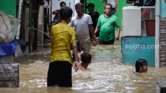 Warga beraktivitas saat banjir yang melanda kawasan Kebon Pala, Jakarta Timur, Senin (10/10/2022). [Suara.com/Alfian Winanto]